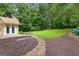 A beautifully landscaped backyard featuring a stone pathway, lush lawn, and detached structure at 205 N Strathmore Dr, Sharpsburg, GA 30277