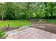 Spacious backyard with a stone patio, lush green lawn, and mature trees at 205 N Strathmore Dr, Sharpsburg, GA 30277