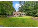 Spacious backyard featuring lush green grass, garden beds and a home in the distance at 205 N Strathmore Dr, Sharpsburg, GA 30277