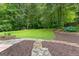 Landscaped backyard with walking path and green grass surrounded by beautiful trees at 205 N Strathmore Dr, Sharpsburg, GA 30277