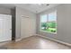 Neutral bedroom featuring wood floors, closet, and a window with a backyard view at 205 N Strathmore Dr, Sharpsburg, GA 30277