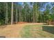 Lush backyard with a mix of green grass and pine straw featuring a wooden deck and mature trees at 55 Etheridge Rd, Temple, GA 30179