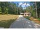 Charming home featuring a long driveway, well-maintained lawn, and inviting front porch nestled amongst the trees at 55 Etheridge Rd, Temple, GA 30179