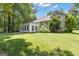 Exterior view of home with large sunroom addition, green grass, and mature trees at 15 Skipton Ct, Sharpsburg, GA 30277