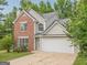 Two-story house featuring a brick facade, attached two-car garage, and manicured lawn with tree at 2576 Abbotts Glen Nw Dr, Acworth, GA 30101