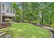 Expansive backyard featuring lush green grass, mature trees and a covered patio area for outdoor enjoyment at 335 S Satinwood Pl, Roswell, GA 30076