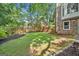Fenced backyard with a well-maintained lawn, complemented by brick home, and privacy from mature trees at 335 S Satinwood Pl, Roswell, GA 30076