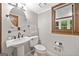 This half bathroom features a pedestal sink, decorative fixtures, and a window that offers natural light at 335 S Satinwood Pl, Roswell, GA 30076