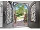 Ornate arched front doors with glass panels open to a view of the landscaped front yard and street at 335 S Satinwood Pl, Roswell, GA 30076