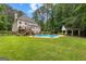 Expansive backyard with a large in-ground pool, patio, deck, pool house, and mature trees at 155 Carrolls Way, Fayetteville, GA 30215