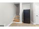Basement staircase and tiled floor with black refrigerator, door, and white trim at 155 Carrolls Way, Fayetteville, GA 30215