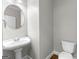 Powder room featuring pedestal sink, round mirror, and wood-look floors at 155 Carrolls Way, Fayetteville, GA 30215