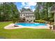 Backyard view showcasing the pool, elevated deck, patio furniture, and lush greenery, perfect for outdoor living at 155 Carrolls Way, Fayetteville, GA 30215