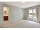 Bright, carpeted bedroom featuring a window and access to an en-suite bathroom at 185 Newfield Dr, Tyrone, GA 30290