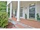 Charming front porch with brick flooring, white columns, bench seating, and manicured greenery at 505 Lighthouse Ln, Peachtree City, GA 30269