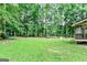 Large grassy backyard with mature trees, a play area, and a glimpse of the back porch, perfect for recreation at 135 Crimson Rdg, Tyrone, GA 30290