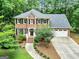 Charming two-story brick home featuring a well-manicured lawn, mature trees, and an attached two-car garage at 135 Crimson Rdg, Tyrone, GA 30290