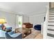 Bright living room with hardwood flooring, brown sofa, blue chairs and a staircase on the side at 135 Crimson Rdg, Tyrone, GA 30290