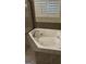 Relaxing bathtub with tile surround and window, ideal for unwinding after a long day at 121 Fountain Oak, Villa Rica, GA 30180