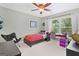 Cozy bedroom with a ceiling fan, a red patterned bed, and a bright window overlooking the yard at 120 Oak Shadow Way, Fayetteville, GA 30215