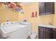 A well-lit laundry room with a washer, dryer, and storage cabinet at 120 Oak Shadow Way, Fayetteville, GA 30215