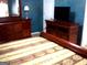 Bedroom with patterned bedspread, wooden furniture and mounted television at 225 Long Creek Dr, Covington, GA 30016