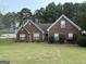 Charming brick home with well-manicured lawn, red shutters, and lush landscaping at 85 Bermuda Run Dr, Covington, GA 30016