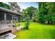 Expansive backyard featuring lush green grass and mature trees surrounding a screened porch at 65 Pine Haven Ct, Carrollton, GA 30116