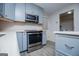 Close up of the kitchen with stainless steel oven and microwave, blue cabinets, and view into laundry at 65 Pine Haven Ct, Carrollton, GA 30116