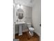 Charming half bath with pedestal sink, round mirror, and wood flooring at 2118 Iverson Se Dr, Smyrna, GA 30080