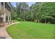 Spacious backyard features well-manicured lawn, wooded surroundings, stone patio, and outbuilding at 52 Olivia Ct, Palmetto, GA 30268