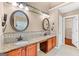 Double vanity bathroom featuring granite counters, decorative mirrors, warm lighting, and a door leading to closet at 52 Olivia Ct, Palmetto, GA 30268