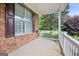 Covered front porch featuring brick detailing, white railings, and windows with decorative shutters at 52 Olivia Ct, Palmetto, GA 30268