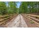 Scenic driveway leading to the property, framed by a wooden fence and surrounded by a beautiful forest at 8129 S Giles Rd, Douglasville, GA 30135
