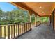 Spacious covered porch with wood ceiling and railing, offering views of the lush surrounding landscape at 8129 S Giles Rd, Douglasville, GA 30135