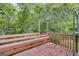Wooden deck with built-in seating and metal canopy frame overlooking a wooded area at 129 Onyx Ct, Carrollton, GA 30116