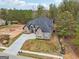 An aerial view of a luxurious two-story home that includes a lush wooded area and a long paved driveway at 4186 Matisse Ln, Fairburn, GA 30213
