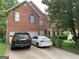 Pristine red brick exterior with attached garages and two vehicles parked in the driveway at 6570 Laurens Way, Stone Mountain, GA 30087
