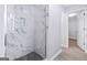 A shower with sleek, marble-like tiling and contrasting dark tile flooring at 984 Wenham Ln, Lawrenceville, GA 30044