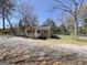 This exterior view of the one-story home includes chain-link fencing and gravel driveway at 927 Dean Patrick Rd, Locust Grove, GA 30248
