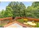 Outdoor deck with a table and chairs overlooking a lush green yard at 2600 Neighborhood Walk, Villa Rica, GA 30180