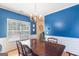 Bright dining room with a wood table, chandelier, blue accent wall, and a large window at 2600 Neighborhood Walk, Villa Rica, GA 30180