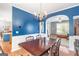 Elegant dining room with a wood table, chandelier, blue accent wall, and wood flooring at 2600 Neighborhood Walk, Villa Rica, GA 30180