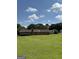 Spacious backyard with lush green grass, mature trees, and glimpses of neighboring houses at 410 Clubland Se Cir, Conyers, GA 30094