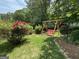 A serene backyard featuring a red swing, lush rose bushes, and manicured garden beds at 404 Windsor Way, Peachtree City, GA 30269
