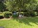 Lush backyard garden featuring shade trees, blue flowers, manicured hedges, and a quaint seating area at 404 Windsor Way, Peachtree City, GA 30269