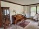 Cozy living room with vintage furniture, a piano, a curio cabinet, and natural light from the window at 404 Windsor Way, Peachtree City, GA 30269