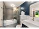 Modern bathroom featuring a tub with glass enclosure, tile accents and a stylish vanity with gold fixtures at 1981 Shalimar Ne Dr, Atlanta, GA 30345
