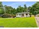 Charming single-story home featuring a manicured lawn, stylish carport, and freshly painted white exterior with black accents at 1981 Shalimar Ne Dr, Atlanta, GA 30345