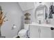 Charming half-bathroom featuring a toilet, vanity with a round mirror, and decorative shelving at 557 Spring Creek Ne Way, Marietta, GA 30068